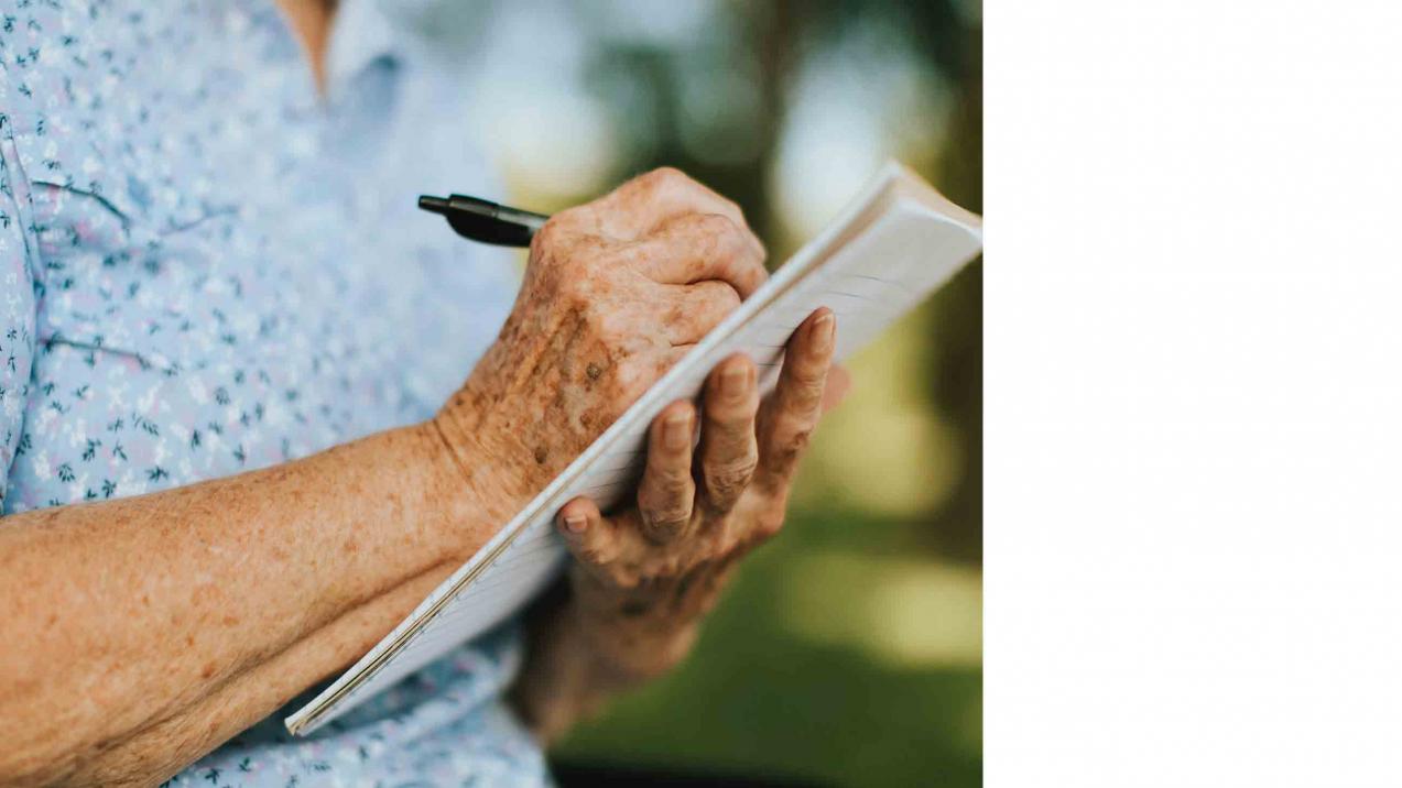 Eine Seniorin schreibt auf einen Notizblock